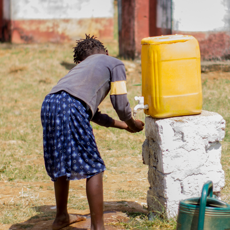 Child in Mozambique filling water container at a well