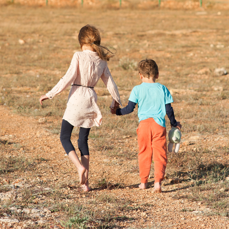 Two Palestinian children walking barefoot in a field