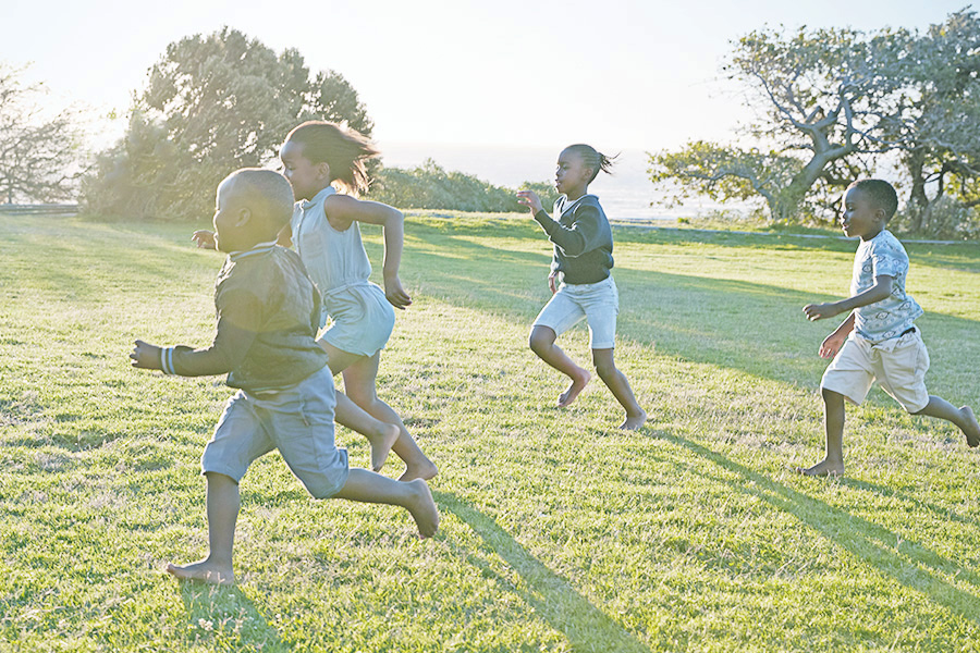 photo of children running across a grassy park at sunset