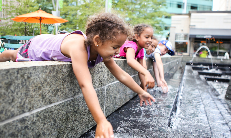 photo of girls playing in a city fountain