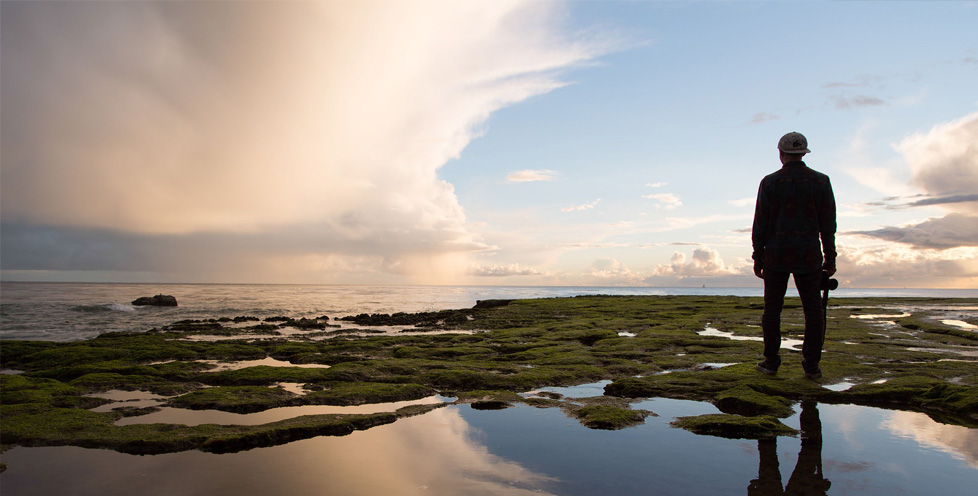 photo of man looking out over water at sunset