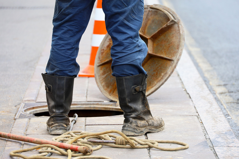 Utility worker opening a manhole cover