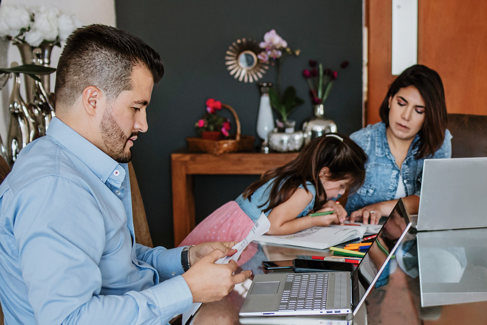Parents and daughter at a table working on laptops